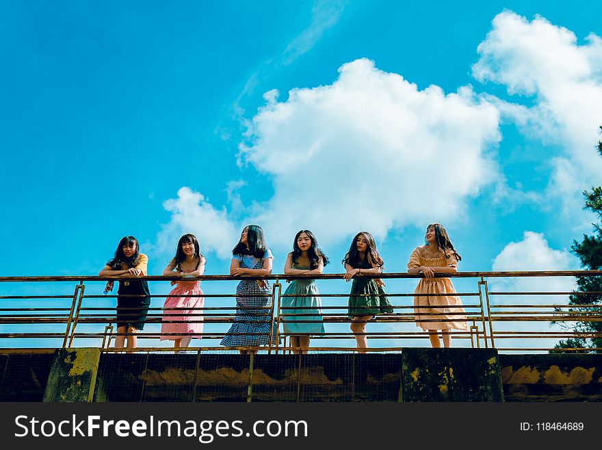 Six Women Wearing Mini Dresses Leaning On Bridge&x27;s Rail