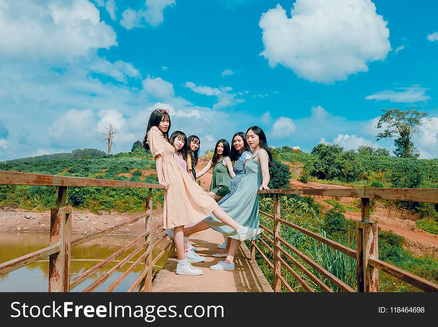 Group Of Women Standing On Brown Bridge