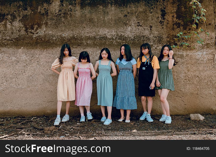 Six Women Leaning on Brown Wall