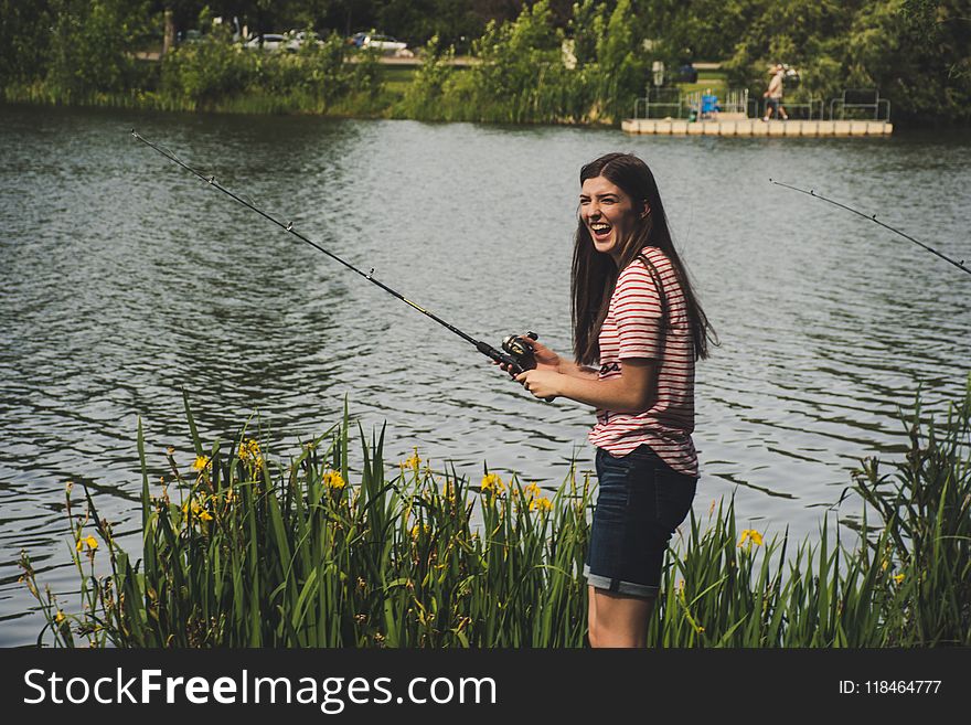 Woman in Red Striped Shirt and Blue Denim Shorts Holding Fishing Rod