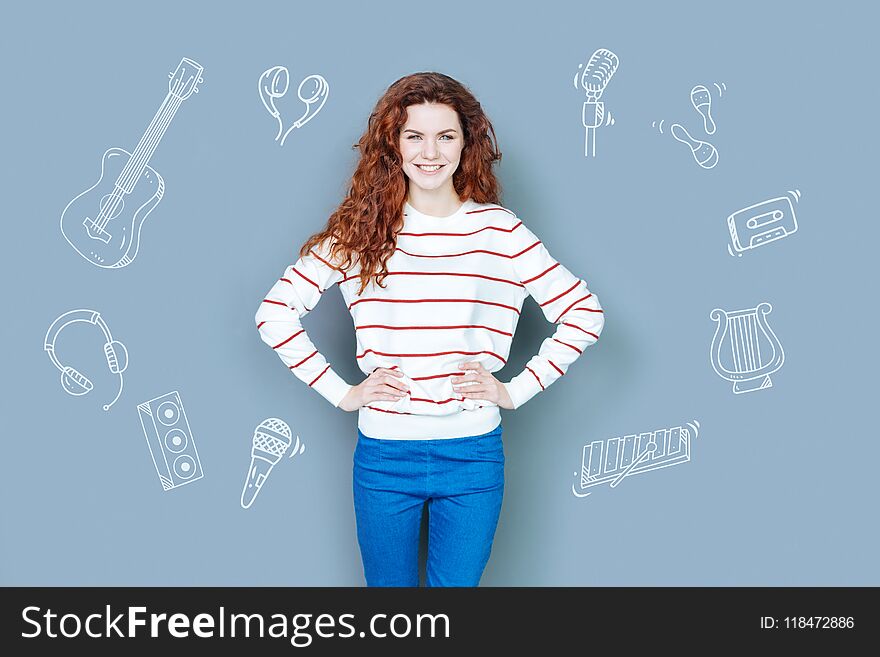 Teacher of music. Enthusiastic friendly music teacher standing with her hands on the hips and smiling. Teacher of music. Enthusiastic friendly music teacher standing with her hands on the hips and smiling