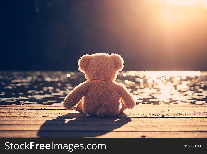 Teddy bear sitting in a pier and looking the water. Teddy bear sitting in a pier and looking the water.