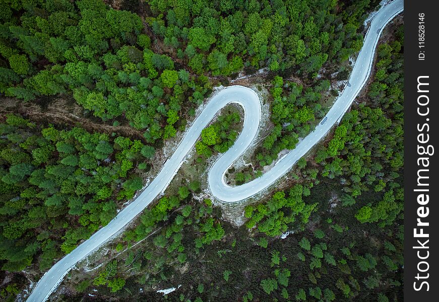 Curved road trough forest , birds eye drone aerial view