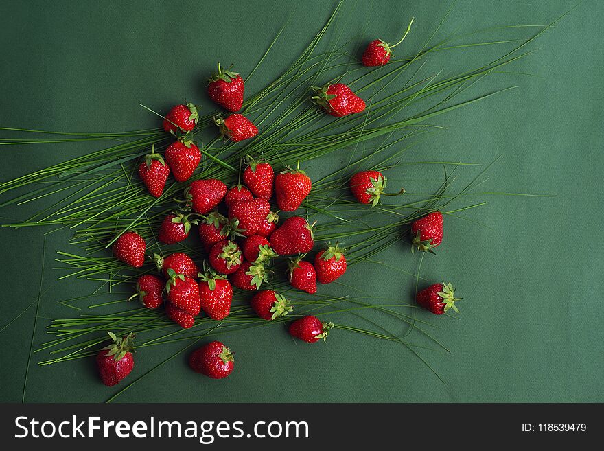 Brightly red natural ripe strawberry in the grass on a green background. Top view. Brightly red natural ripe strawberry in the grass on a green background. Top view.