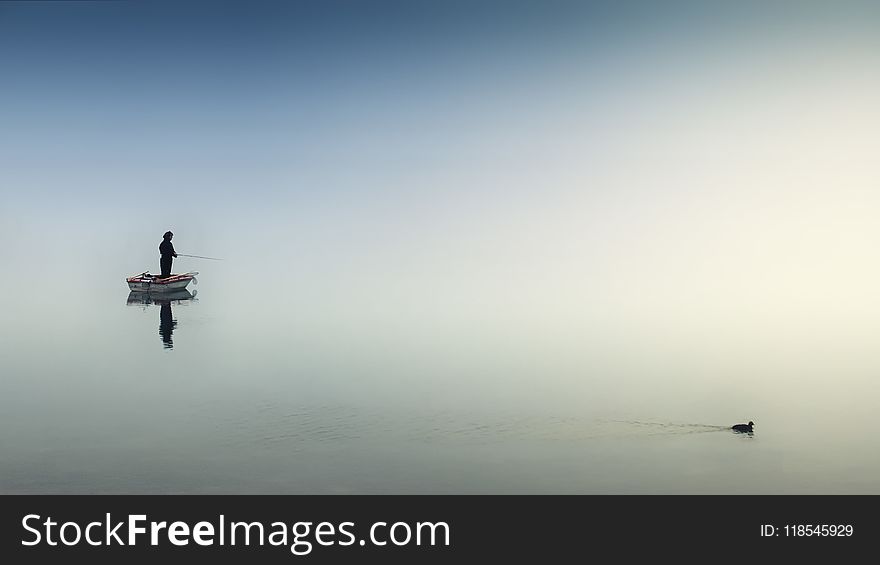 Person on White Boat Fishing on Body of Water