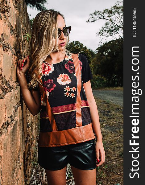 Woman Wearing Black Floral Short-sleeved Shirt and Black Pants Standing Near Wall