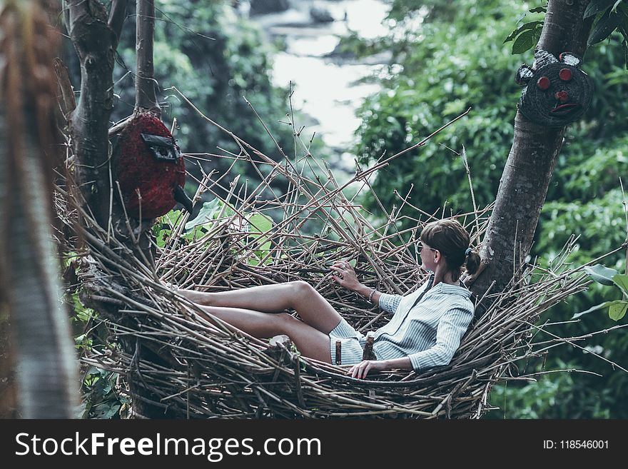 Woman Wearing Gray Long-sleeved Shirt on Nest Hammock in Selective Focus Photography