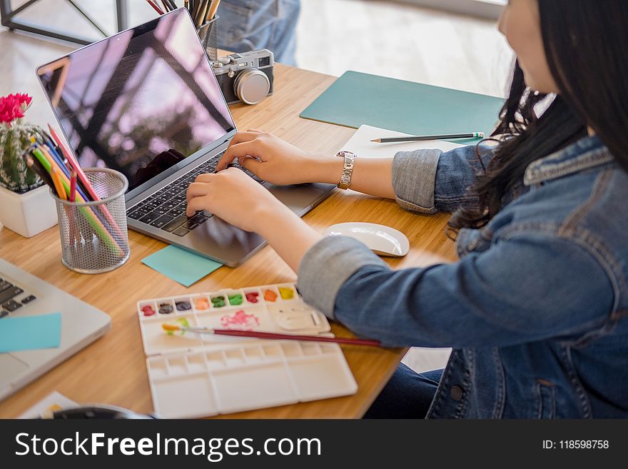 Woman Using Black Laptop While Leaning on Brown Wooden Table