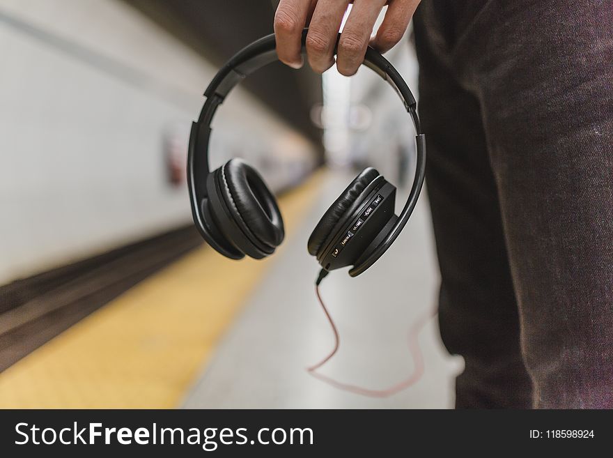 Shallow Focus Photography of Person Holding Headphones