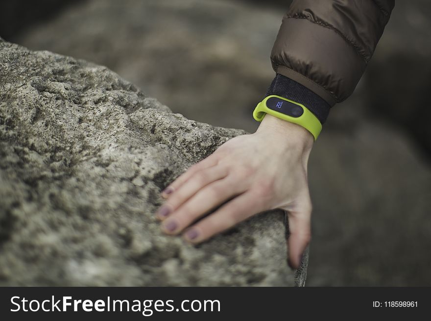 Person Wearing Yellow Fitness Band Holding Rock
