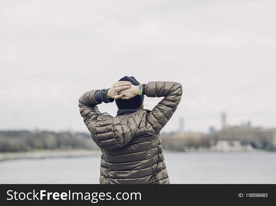 Person Holding Head Facing Body of Water