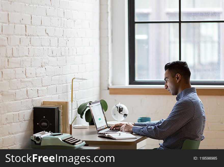 Man Sitting on Green Chair While Using Laptop