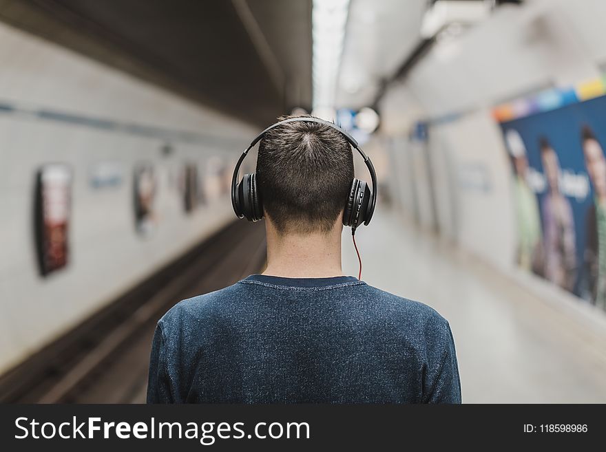 Man Wearing Black Headphones Beside Train Rail