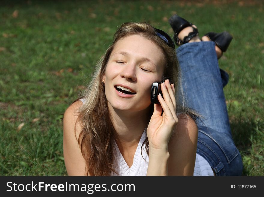 younger woman rests upon green herb and talks on mobile telephone. younger woman rests upon green herb and talks on mobile telephone