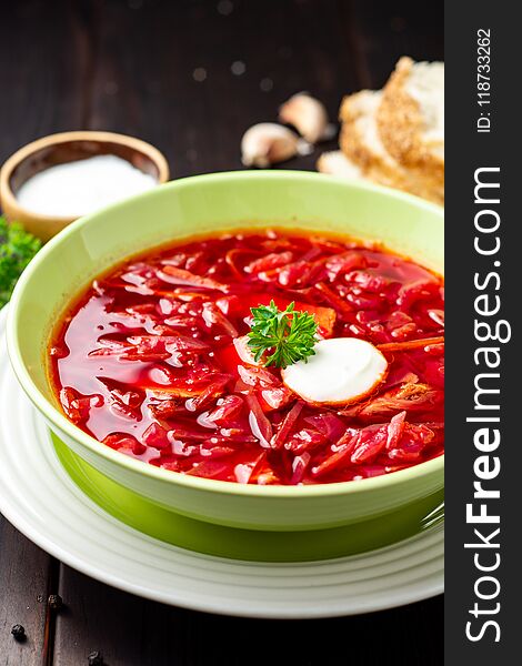 Borsch - traditional Ukrainian and Russian beetroot soup on dark wooden background. Selective focus.