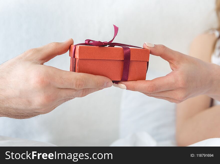 cropped view of man presenting red gift box to his girlfriend. cropped view of man presenting red gift box to his girlfriend