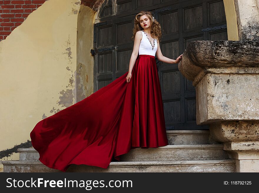 Pretty woman in evening flying dress at stairway