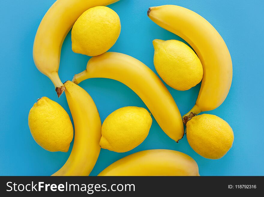 Yellow bananas and lemons on bright blue paper, trendy flat lay. fruits modern image, top view. juicy summer vitamin abstract background. pop art style. minimalism pattern