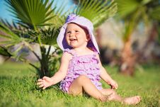 Portrait Of A Happy Girl On Vacation. A Girl In Purple Is Sitting On The Lawn. Royalty Free Stock Image