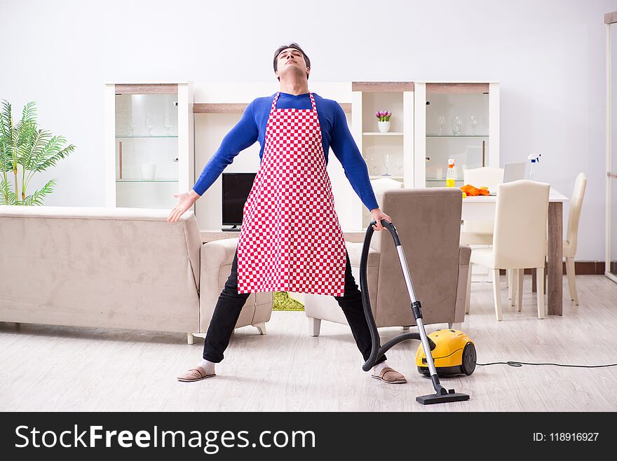 The young man vacuum cleaning his apartment