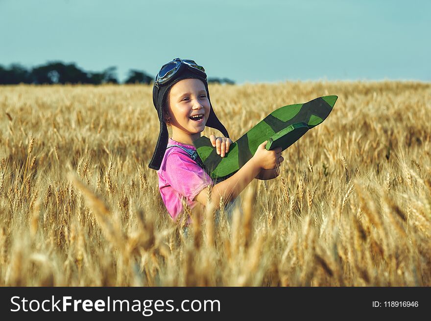 Cheerful girl in a field of wheat playing with a model aircraft