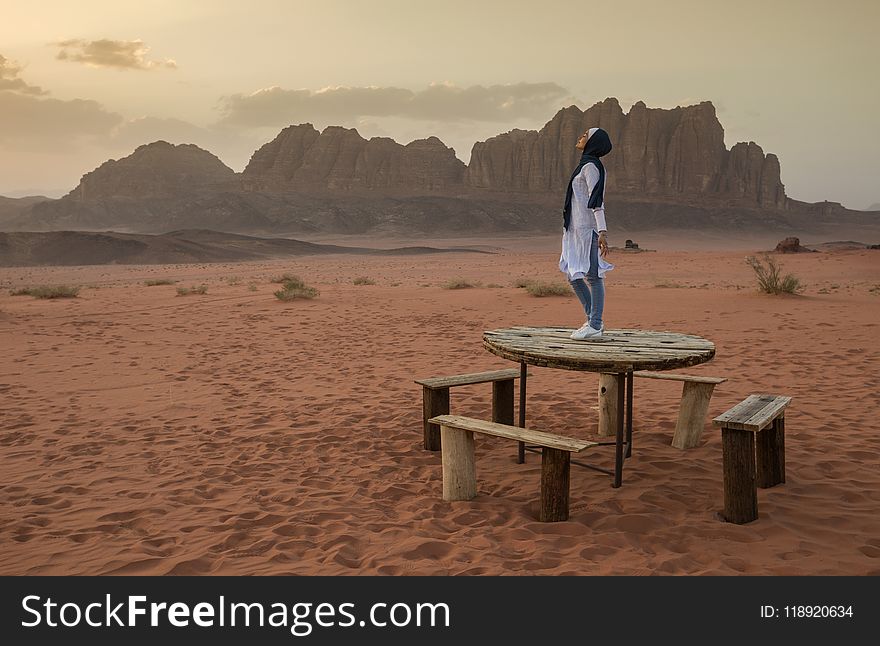 Person Stands on Brown Wooden Table