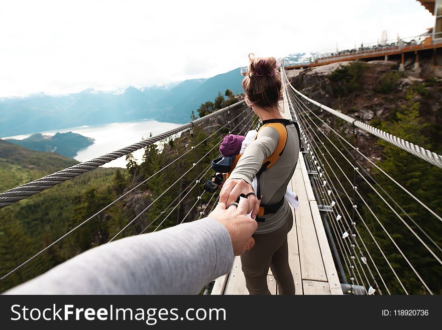 Woman With Yellow Backpack Standing on Hanging Bridge With Trees