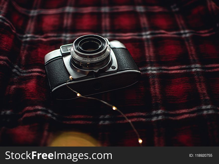 Black and Gray Point-and-shoot Camera on Red, Black, and White Plaid Textile