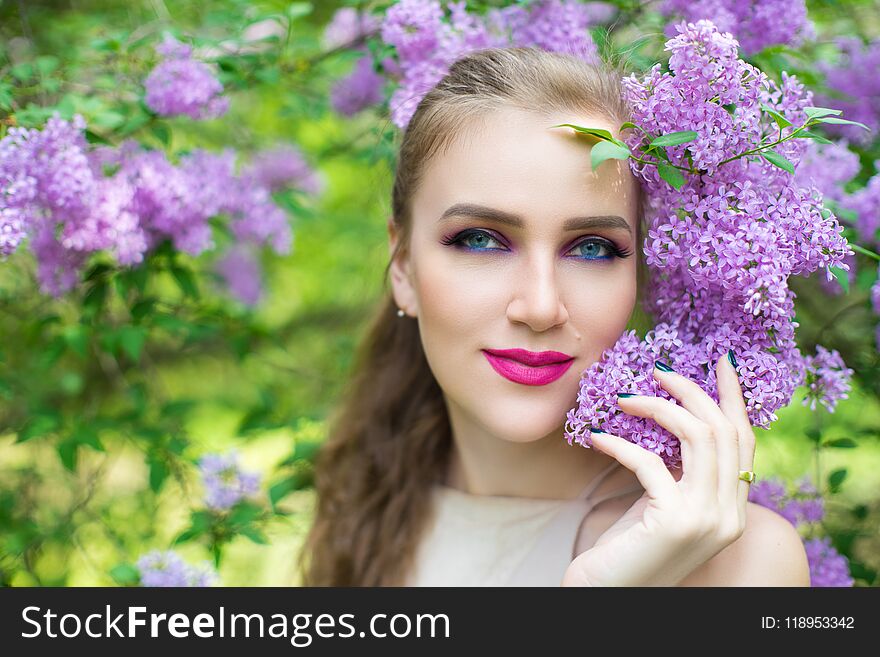Beautiful girl in a spring garden standing near blossoming flowering tree. Young woman in a fashion dress in the park near the bush blossom. Smell aromatic nature. Horizontal photo banner free place. Beautiful girl in a spring garden standing near blossoming flowering tree. Young woman in a fashion dress in the park near the bush blossom. Smell aromatic nature. Horizontal photo banner free place