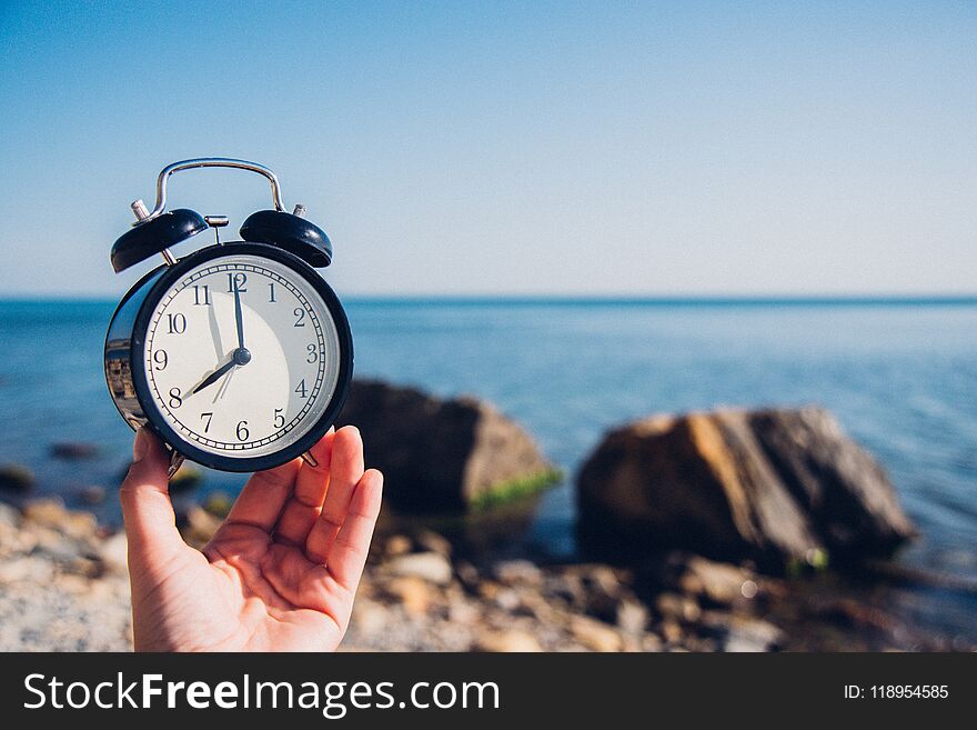 Hand Hold Watch On Beach Background.Alarm Clock On Sea And Sand Background Different Time With Summer Vacation.Vacation Time Conce