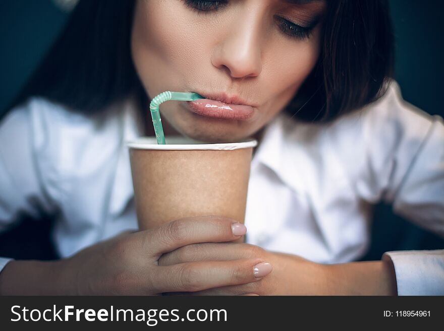 Pretty lady looking down in her coffee cup. Close up portrait of beautiful woman drinking coffee from green straw with her lips rolled. s. Pretty lady looking down in her coffee cup. Close up portrait of beautiful woman drinking coffee from green straw with her lips rolled. s