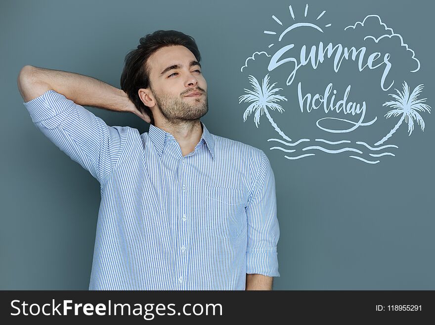 Summer holidays. Calm handsome student touching his nape and smiling while looking forward to having summer holidays. Summer holidays. Calm handsome student touching his nape and smiling while looking forward to having summer holidays