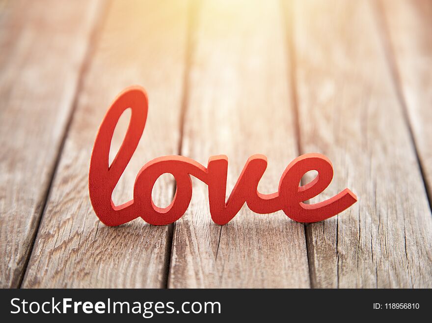 Word love on old wooden background in sunset