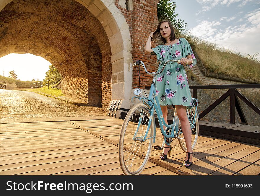 Summer day and girl on vintage bicycle on wooden bridge