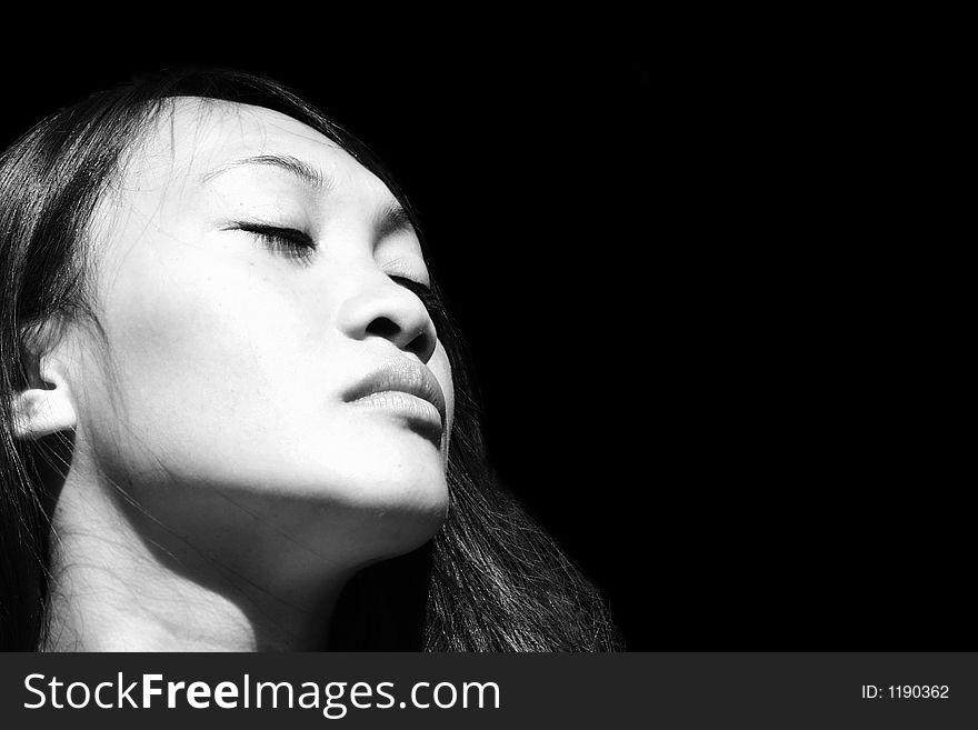 Profile portrait of a beautiful young asian woman in front of black background. Profile portrait of a beautiful young asian woman in front of black background