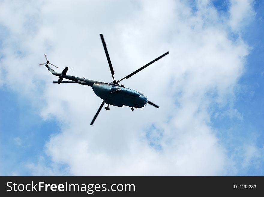 Helicopter flying on a cloudy sky as background