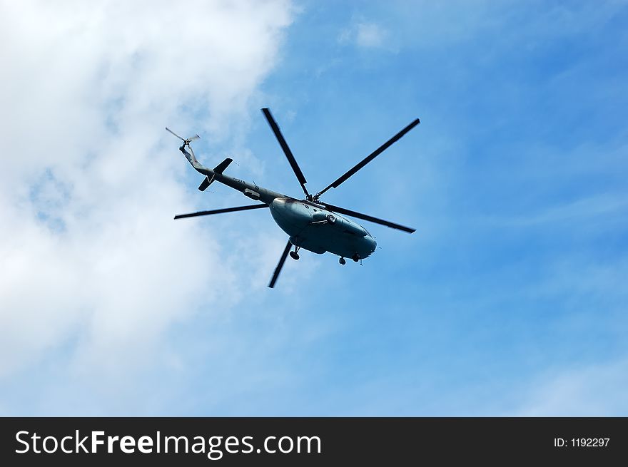 Helicopter flying on a cloudy sky as background