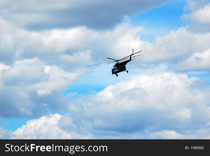 Helicopter flying on a cloudy sky as background