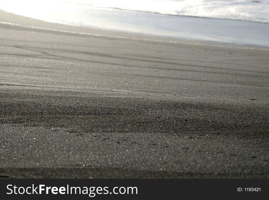 Freshly washed sand at the waters edge catches the low sun. Freshly washed sand at the waters edge catches the low sun