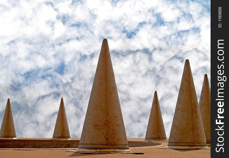 Rusty metal cones against cloudy sky