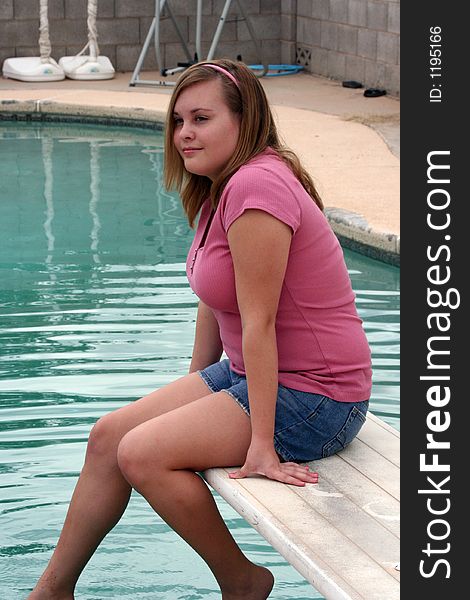 Teenage girl sitting on a diving board. Teenage girl sitting on a diving board.