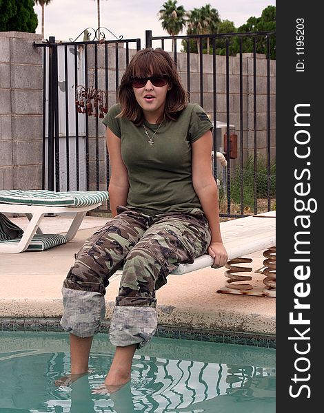 Girl sitting on a diving board wearing camouflage and sunglasses. Girl sitting on a diving board wearing camouflage and sunglasses.