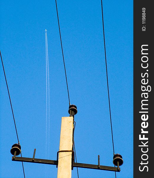 Jet plane trace and electricity pillar with wires