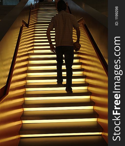 A man walking up an illuminated staircase in a modern building in Germany. A man walking up an illuminated staircase in a modern building in Germany.