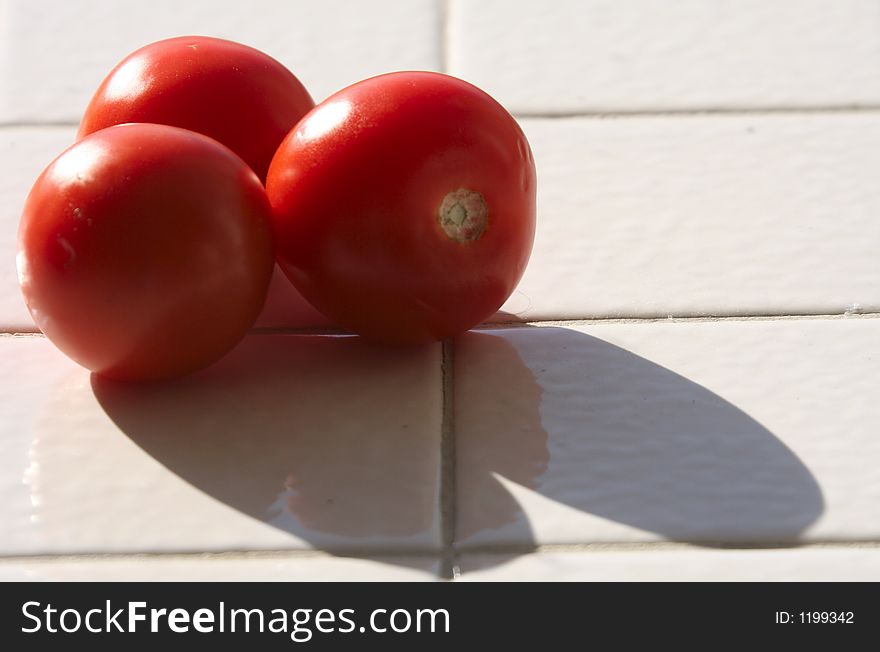 Tomatoes and their shadows on a tiled counter