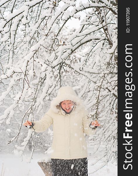Young woman shaking the snowy tree and laughing. With some motion blur. Young woman shaking the snowy tree and laughing. With some motion blur.