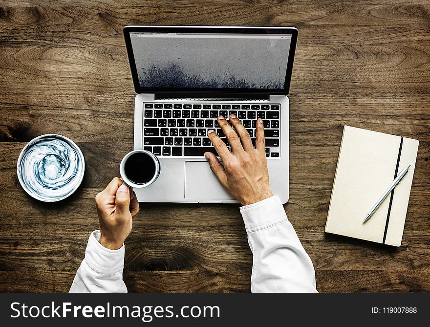 Person Holding Black Ceramic Cup and Macbook Pro