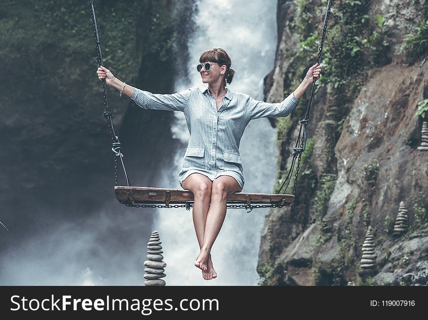 Photo of Woman Riding Swing in Front of Waterfalls