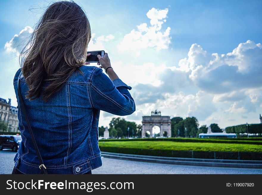 Woman Wearing Blue Denim Jacket Standing While Holding Smartphone