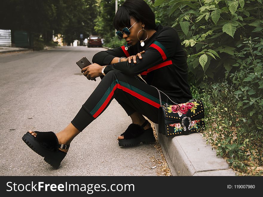 Woman Sitting on Gray Concrete Sidewalk Taken